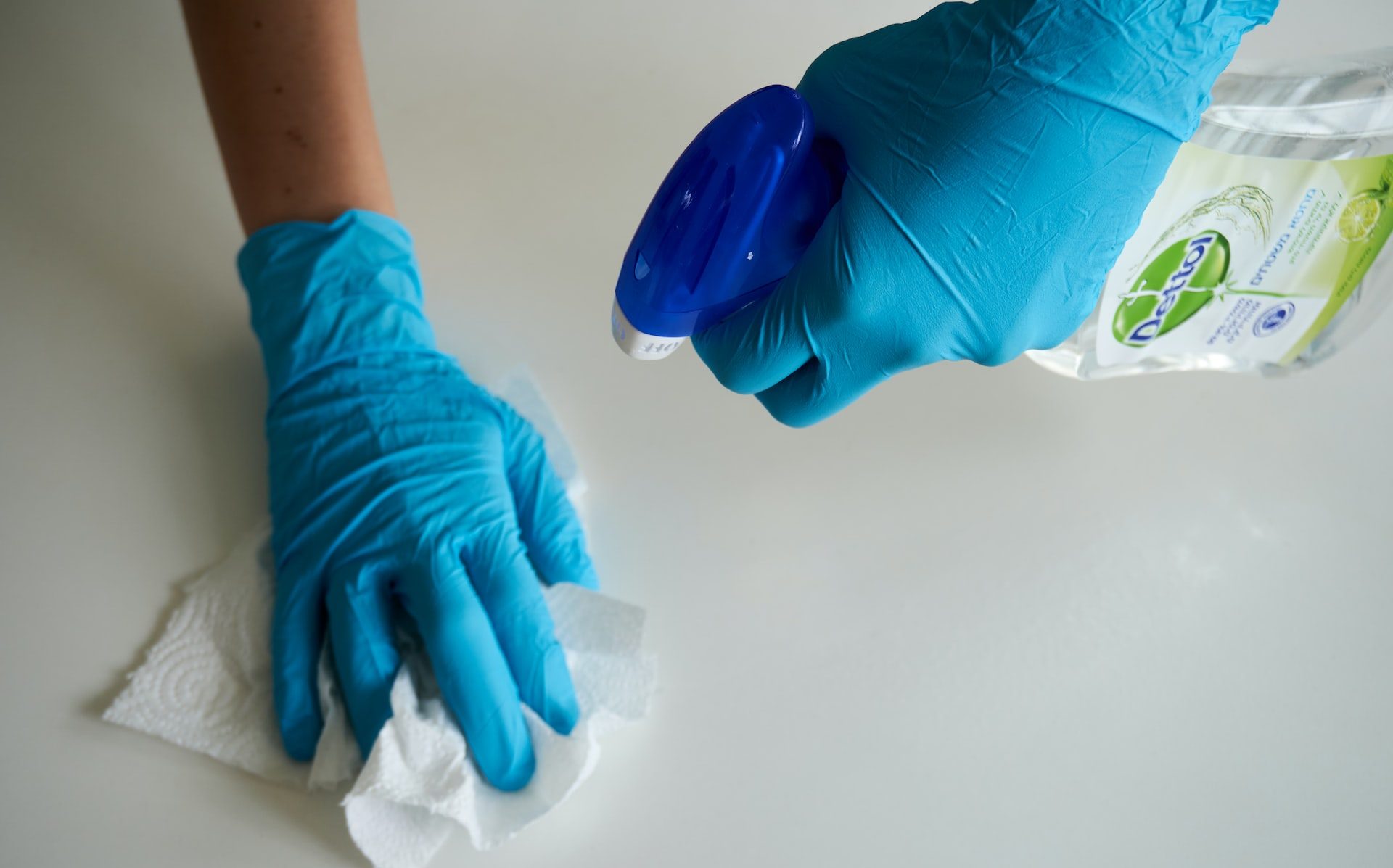 person in blue gloves holding white textile