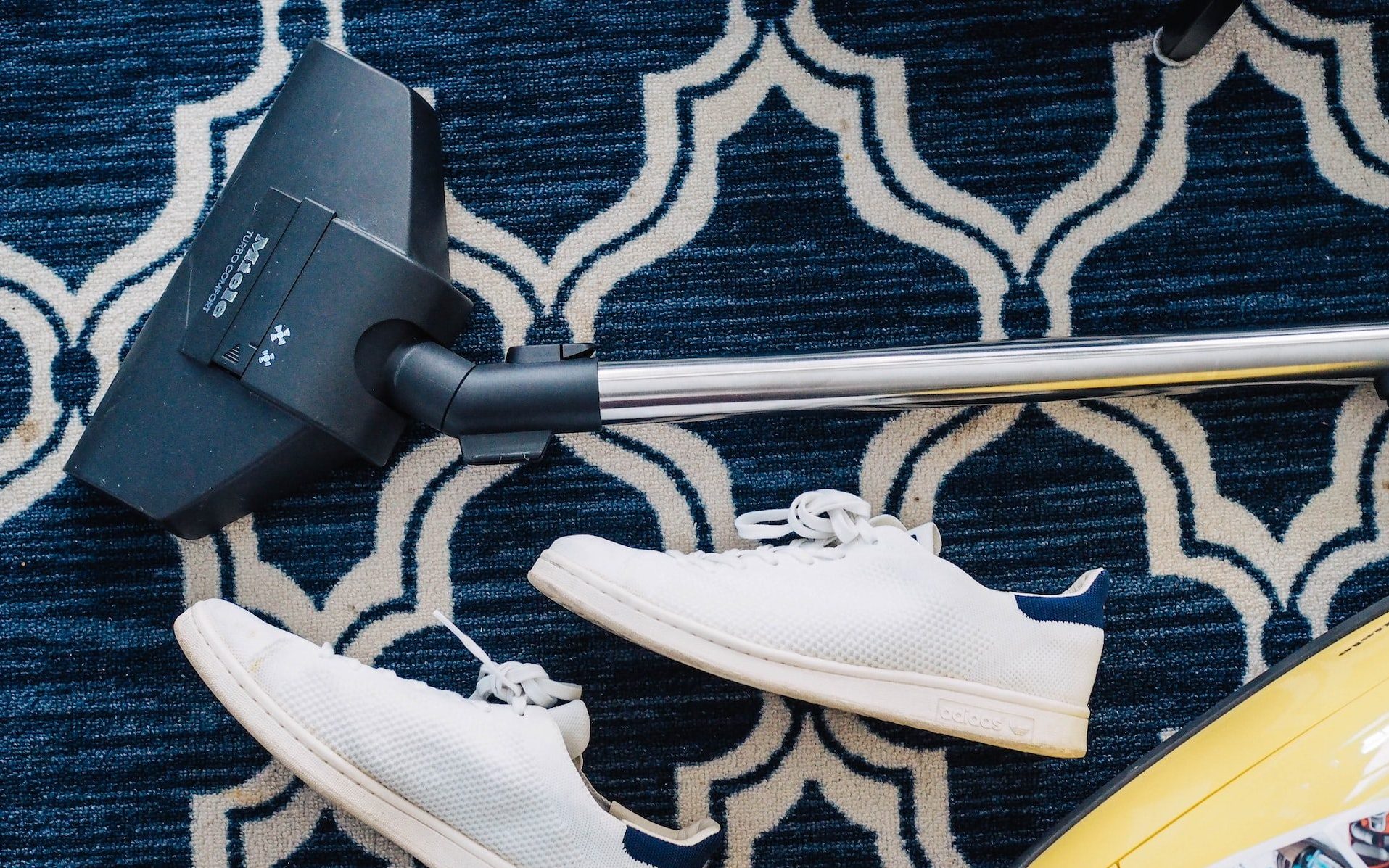 pair of white sneakers beside vacuum cleaner